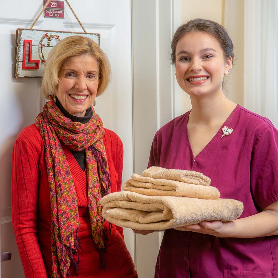 A team member delivering fresh linens to a resident at Summit Glen